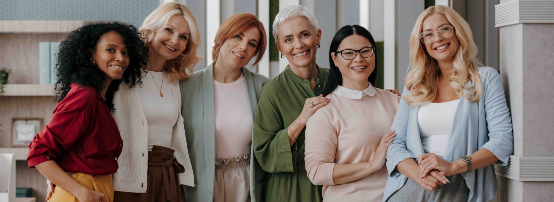 Group of mature businesswomen bonding and smiling while standing in the office together